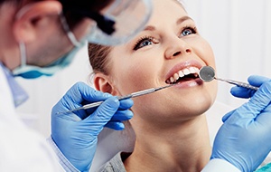 A female patient having her teeth looked at by a dentist