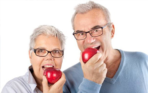 Senior man and woman eating red apples