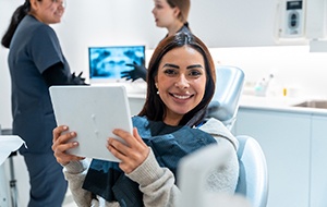 Patient smiling while holding mirror in treatment chair