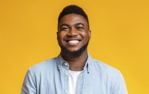 man smiling in front of a yellow background 