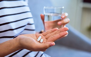 Close-up of person holding painkillers and glass of water