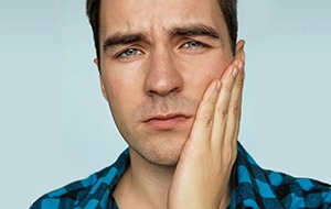 Close-up of man with oral discomfort rubbing his cheek