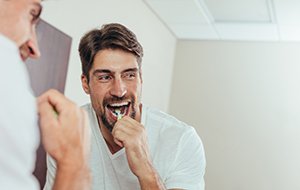 Man brushing his teeth in the bathroom mirror