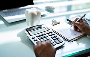 a calculator, notepad, and a model of a tooth sitting on a desk