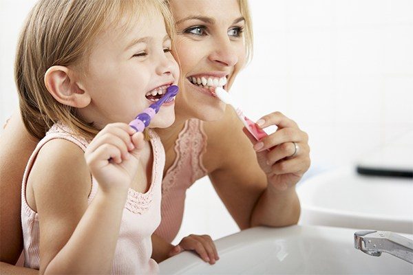 Mother and daughter brushing teeth