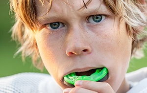 Teen boy placing green mouthguard