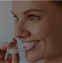 Woman placing Invisalign tray in her mouth