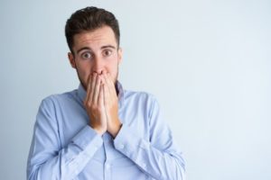 Concerned man covering his mouth needs to visit his dentist