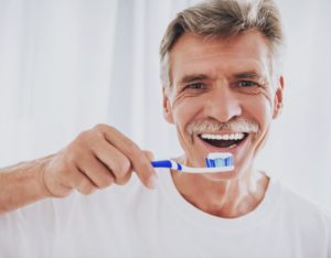 older man about to brush his dental implants