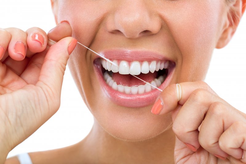 Woman smiling and flossing her teeth