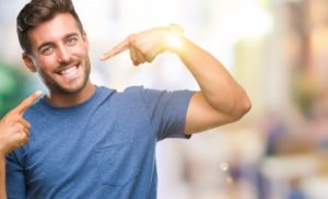 man pointing to his smile after seeing his cosmetic dentist