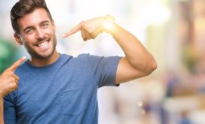 man pointing to his smile after seeing his cosmetic dentist 