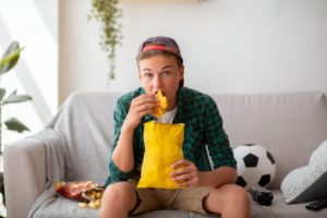 teenager watching football eating unhealthy food