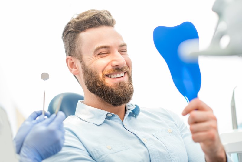 patient who had dental implant surgery smiling in mirror