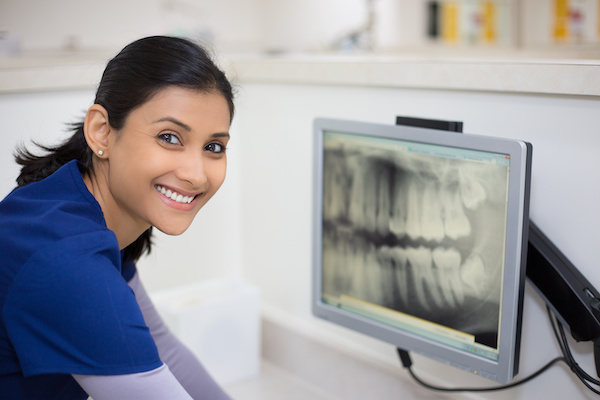 woman in scrubs looking at digital dental x-ray