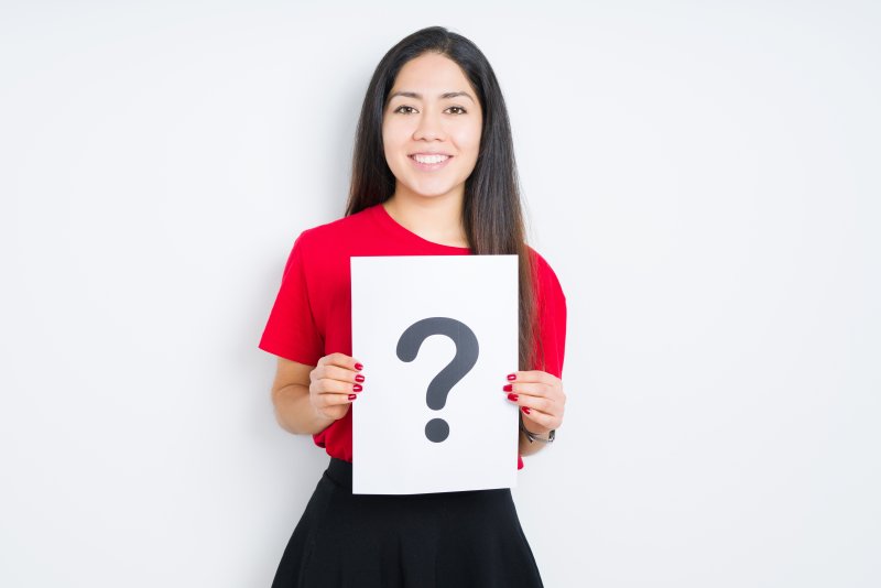 a woman smiling with a question mark in her hand