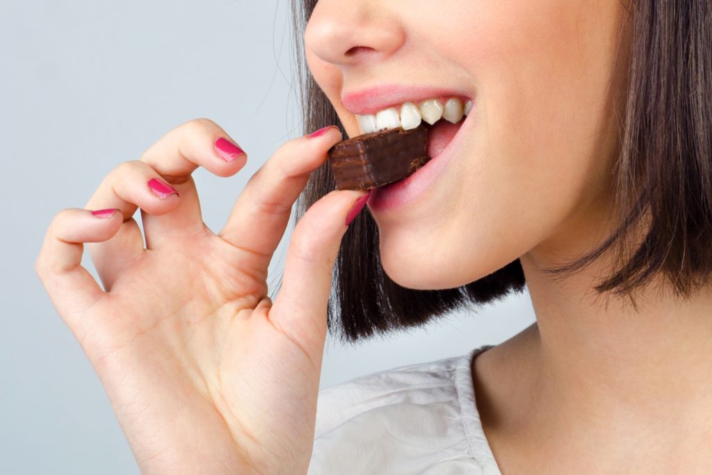 Woman smiling while biting into brownie