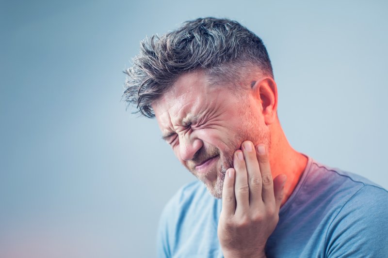 person with toothache holding their cheek