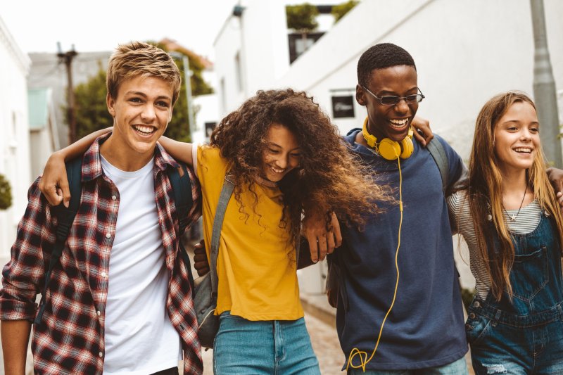 A group of teenagers smiling after their cosmetic dentistry treatments