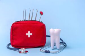 Fake tooth next to a red emergency bag containing dental instruments